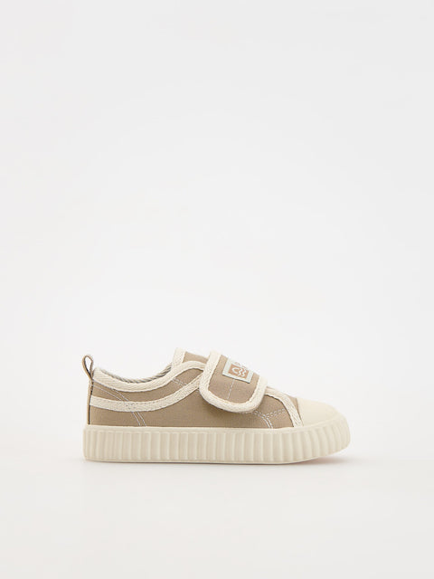 Beige sneaker with white sole on a light beige background
