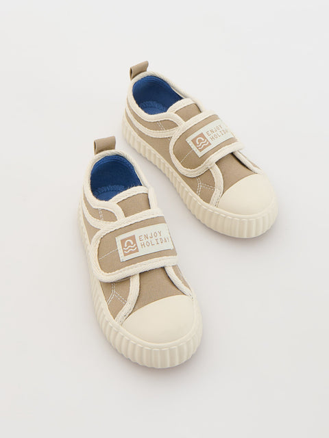 Pair of beige children's sneakers with blue interior on a light gray background