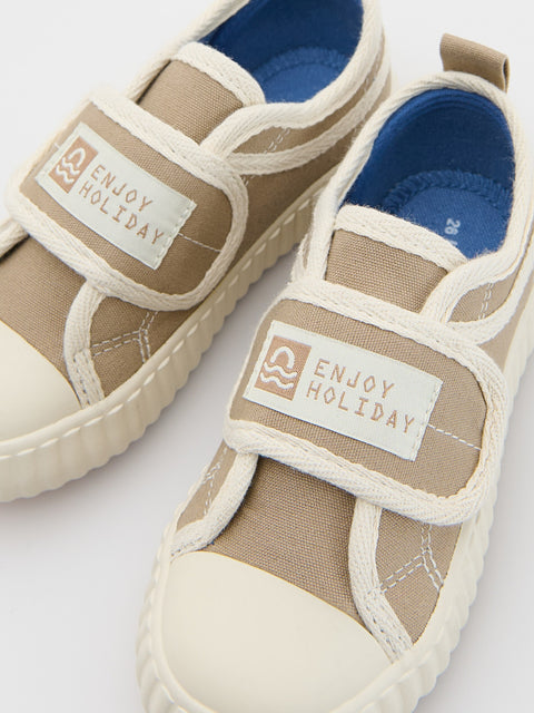 Pair of beige children's shoes with 'Enjoy Holiday' label on a white background