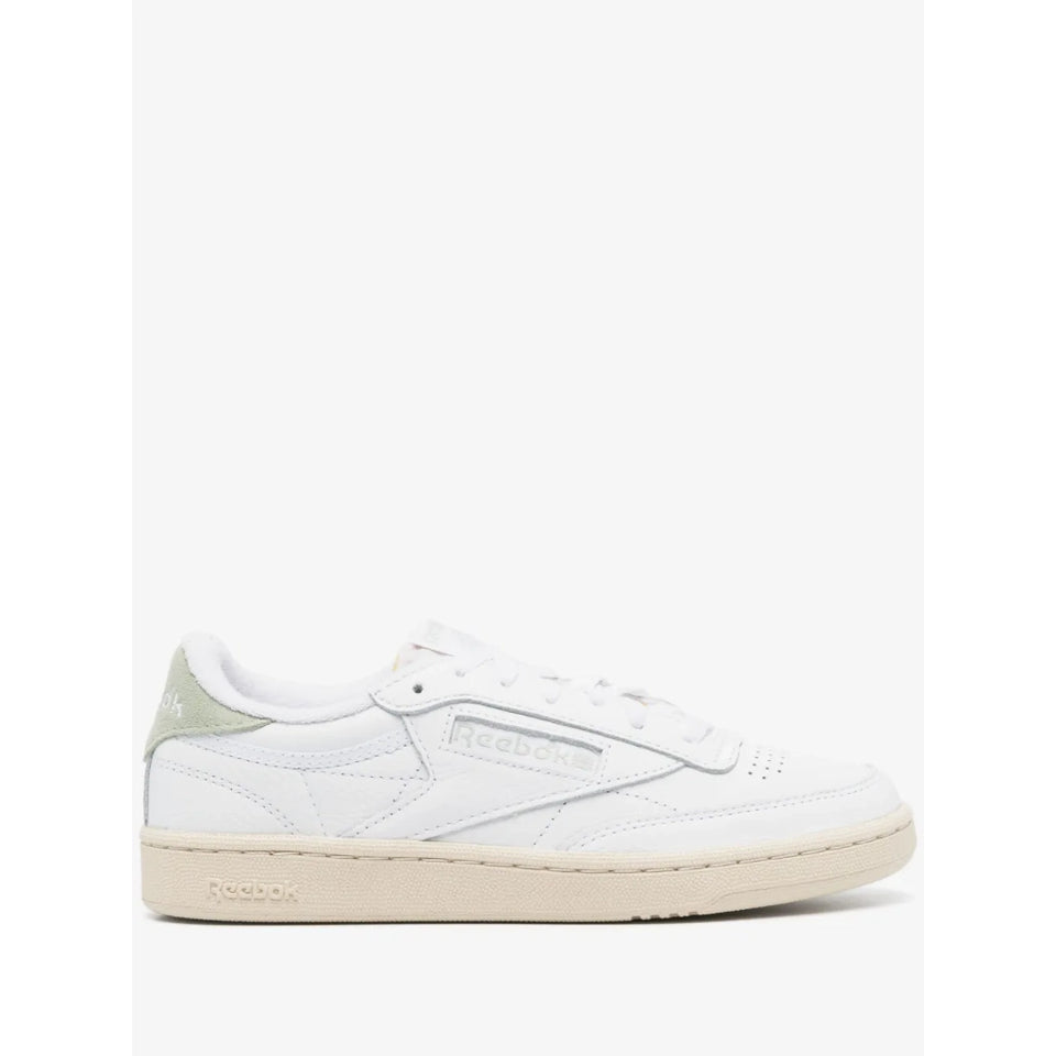 A Reebok Classic Cube sneaker in white leather with a light sage green heel tab and a beige rubber sole, shown from a side profile on a white background.