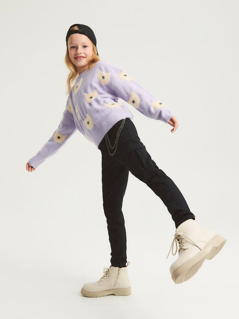 Child wearing a light purple sweater with floral patterns, black pants, and beige boots on a white background