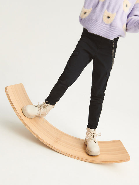 Person using a wooden balance board on a plain background