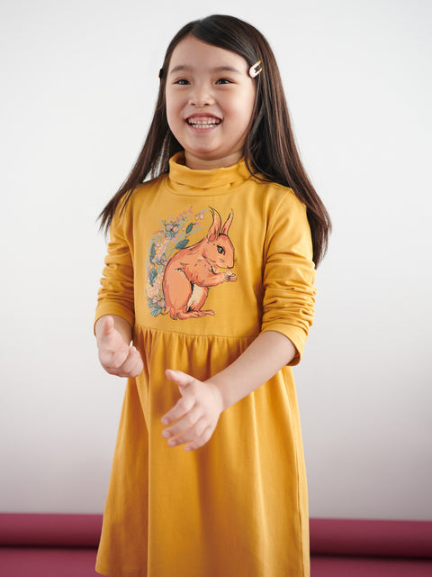 Young girl wearing a yellow dress with a squirrel design on a white background