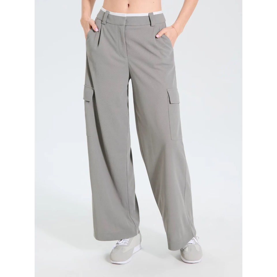 A person wearing light gray wide-leg cargo pants with side flap pockets, shown from the waist down against a plain light gray studio background.