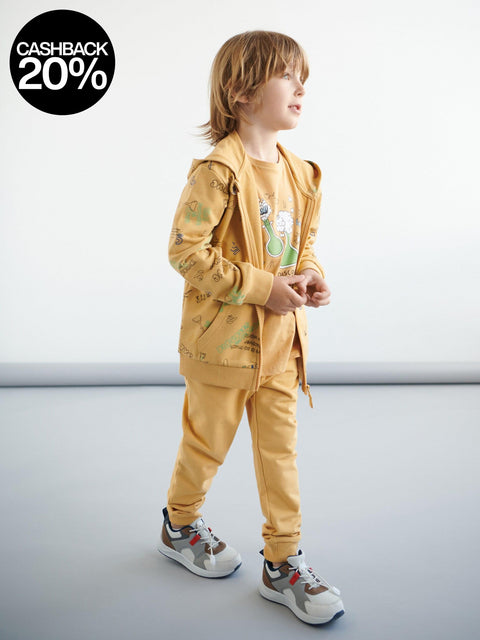 Child wearing a yellow outfit with a dinosaur print on a white background