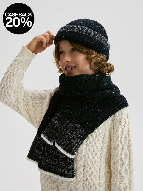 Child wearing a black knit hat and scarf with a white background