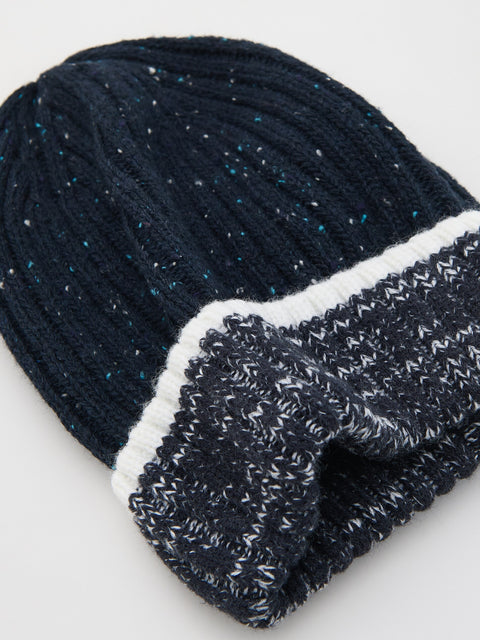 Dark blue knit beanie with white trim on a light gray background