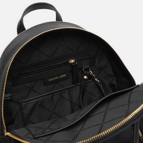 Black quilted backpack with gold zippers on a light gray background