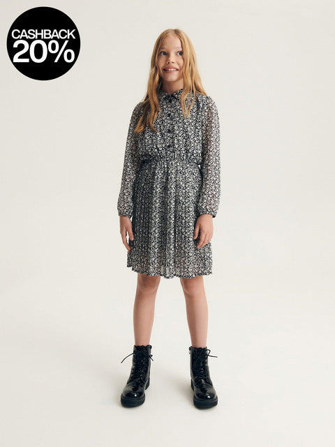 Girl wearing a black and white patterned dress with black boots on a white background, featuring a cashback 20% offer.