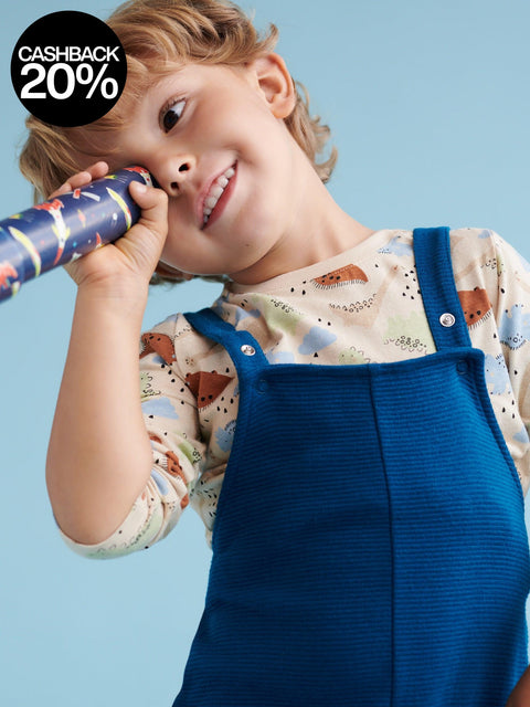Child wearing a blue dress overalls holding a toy against a light blue background with a cashback offer overlay.