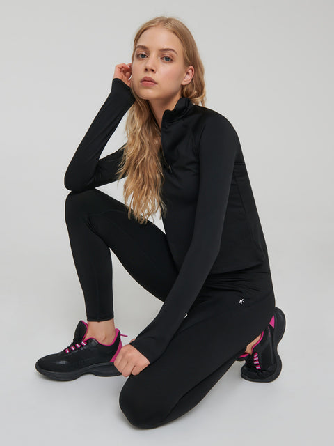 Woman wearing a black tracksuit with pink accents on a white background