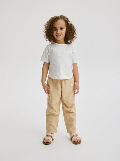 Child wearing a white t-shirt and beige pants on a white background