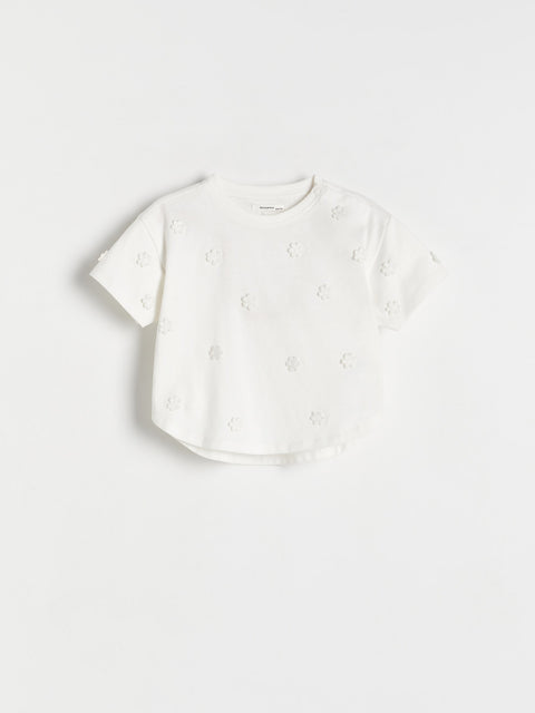 White blouse with floral embroidery on a light gray background