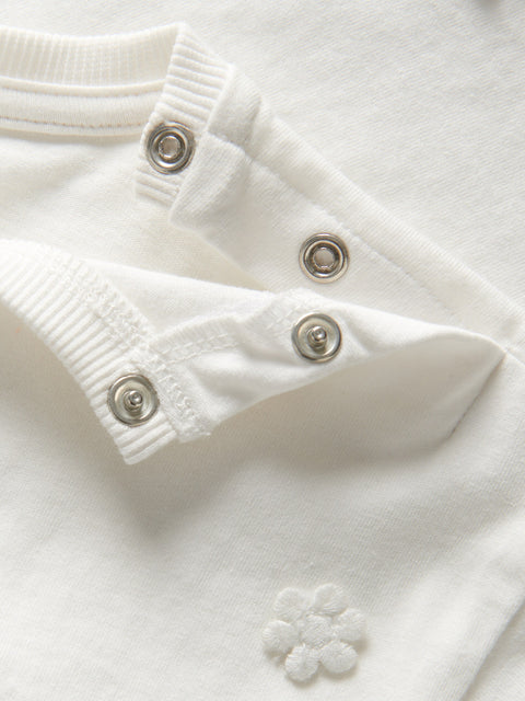 Close-up of a white garment with button details on a light background