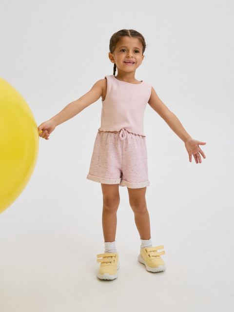 Young girl in pink outfit standing against a white background