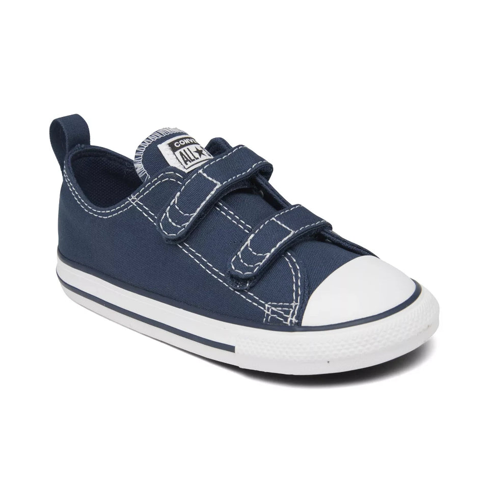 A navy blue canvas toddler low-top sneaker with white contrast stitching, a white rubber toe cap, and two adjustable hook-and-loop straps, shown on a white background.