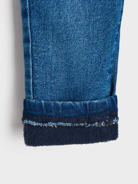 Close-up of blue jeans with a textured hem on a white background