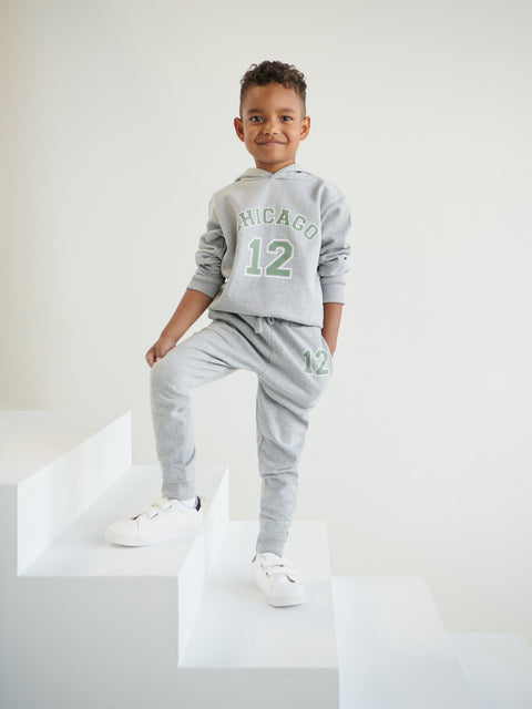 Child wearing a gray 'Chicago 12' sweatshirt and pants on a white background