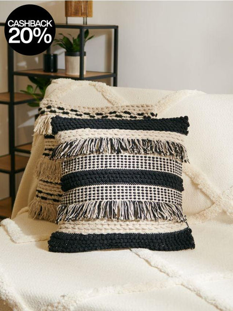 Black and white woven pillow with fringe on a white surface