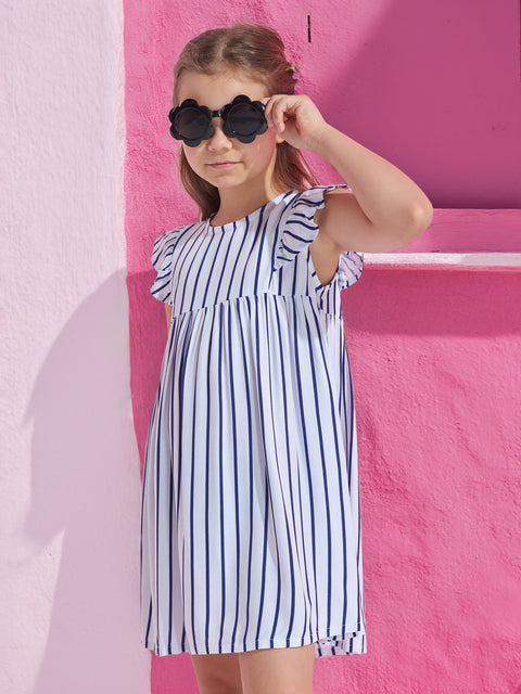 Young girl wearing a striped dress and heart-shaped sunglasses against a pink background
