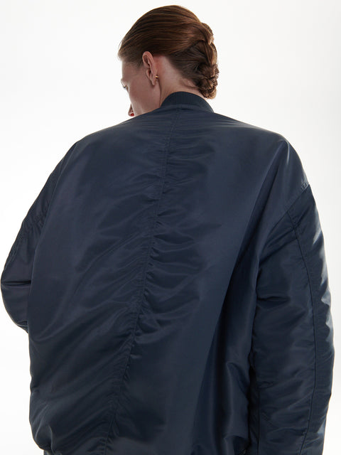 Person wearing a navy blue bomber jacket on a white background