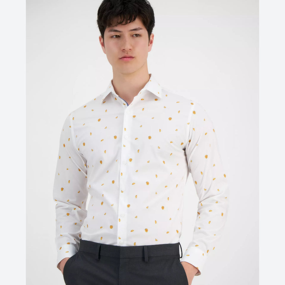 A man wearing a white long-sleeve button-down shirt with a small gold abstract pattern, paired with dark trousers, against a plain light gray background.