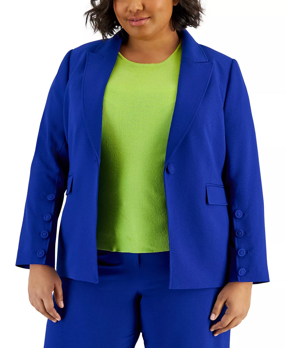 Woman wearing a blue blazer over a green top and blue pants on a white background