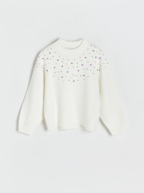 White sweater with colorful polka dots on a light gray background