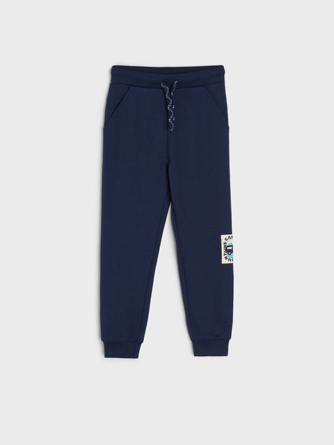 Navy blue jogger pants with a small patch on a white background