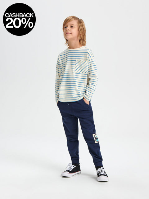 Child wearing a striped shirt and navy pants on a white background