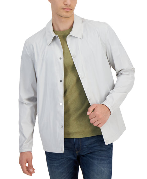 Man wearing a light gray jacket over a green shirt with a white background