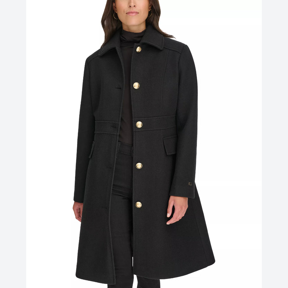 A woman wearing a black mid-length coat with large gold buttons, shown against a plain white studio background.