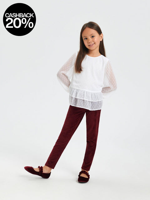 Young girl wearing a white top and burgundy pants on a white background