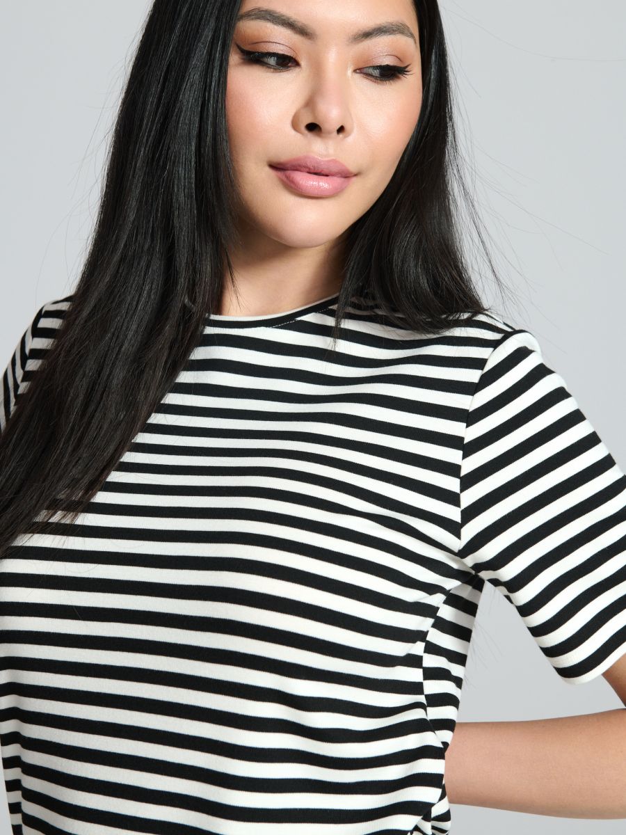 Woman wearing a black and white striped shirt against a gray background