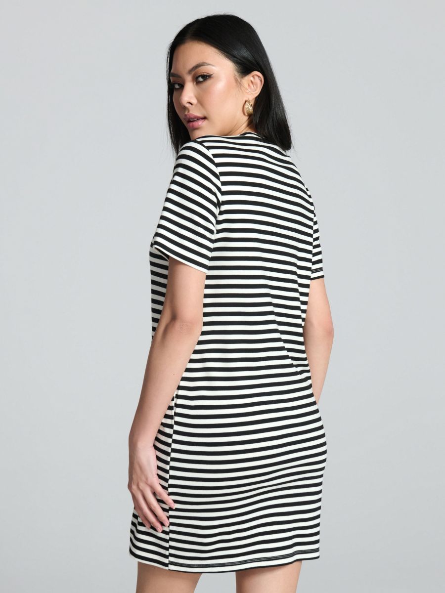 Woman wearing a black and white striped dress against a gray background