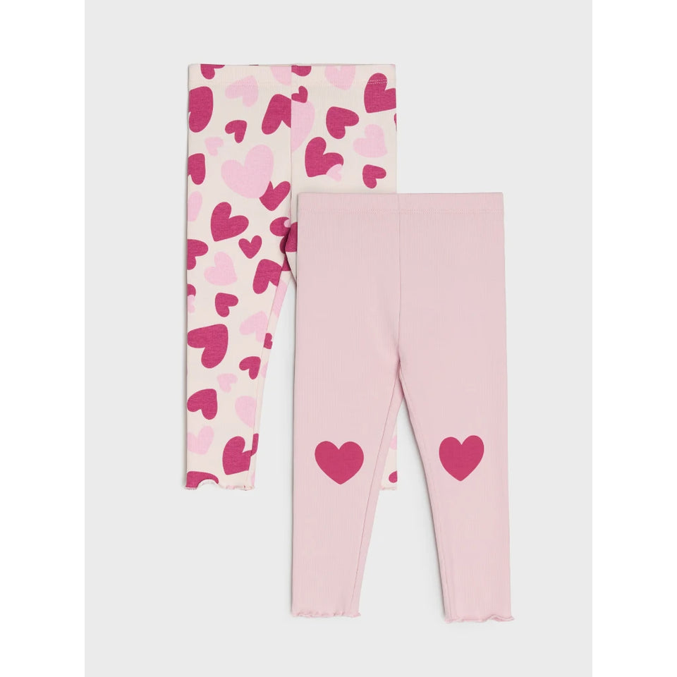 A pair of children's leggings shown flat against a light gray background. One legging has an allover pattern of pink and magenta hearts on a cream base, and the other is solid light pink with two larger magenta heart graphics on the lower legs.