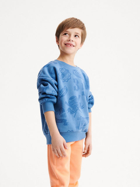 Child wearing a blue sweater with floral patterns on a white background