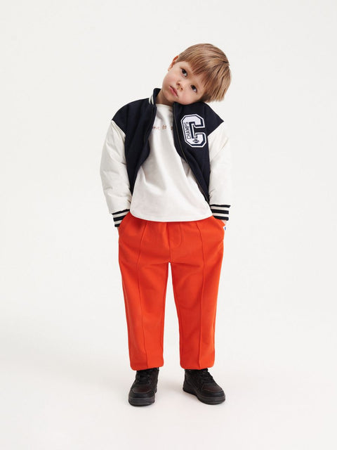 Child wearing a varsity jacket with a letter 'C' on a white background