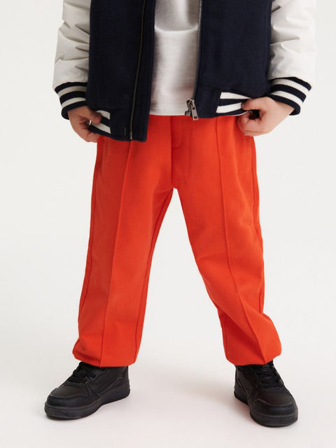 Person wearing bright orange pants with a white background