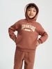 Child wearing a brown hoodie with 'Wild Adventure' text on a white background