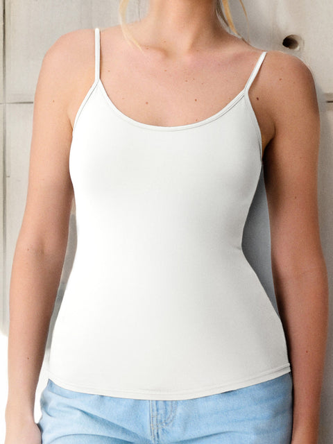 Person wearing a white tank top and light blue jeans against a neutral background