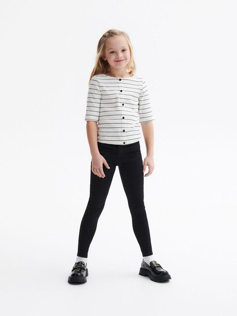 Young girl wearing a striped shirt and black leggings on a white background