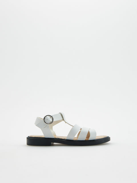 White sandal with black sole on a light gray background