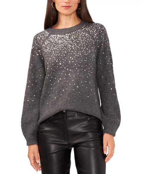 Woman wearing a gray sweater with sequin details and black leather pants on a white background