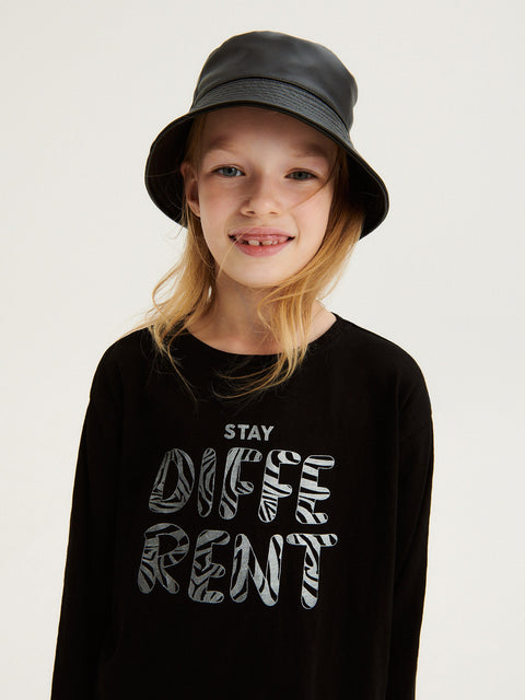 Child wearing a black shirt with 'STAY DIFFERENT' text and a gray bucket hat on a light background