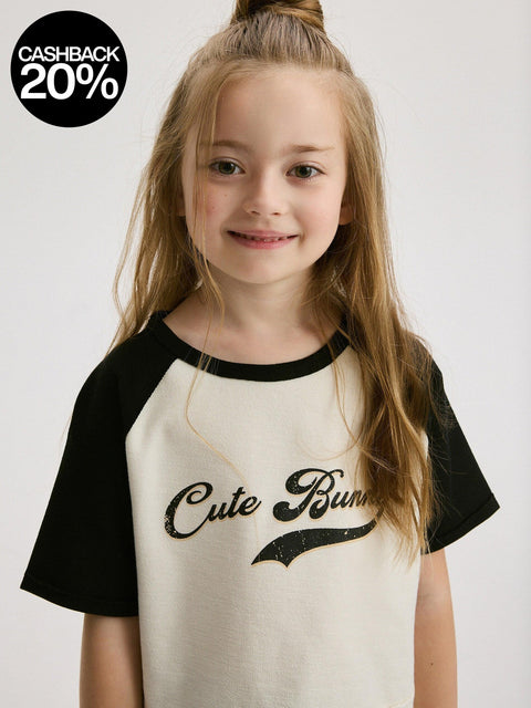 Young girl wearing a black and white shirt with 'Cute Bunny' text on a plain background