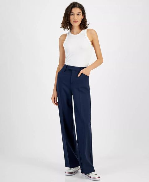 Woman wearing a white sleeveless top and navy wide-leg pants on a white background