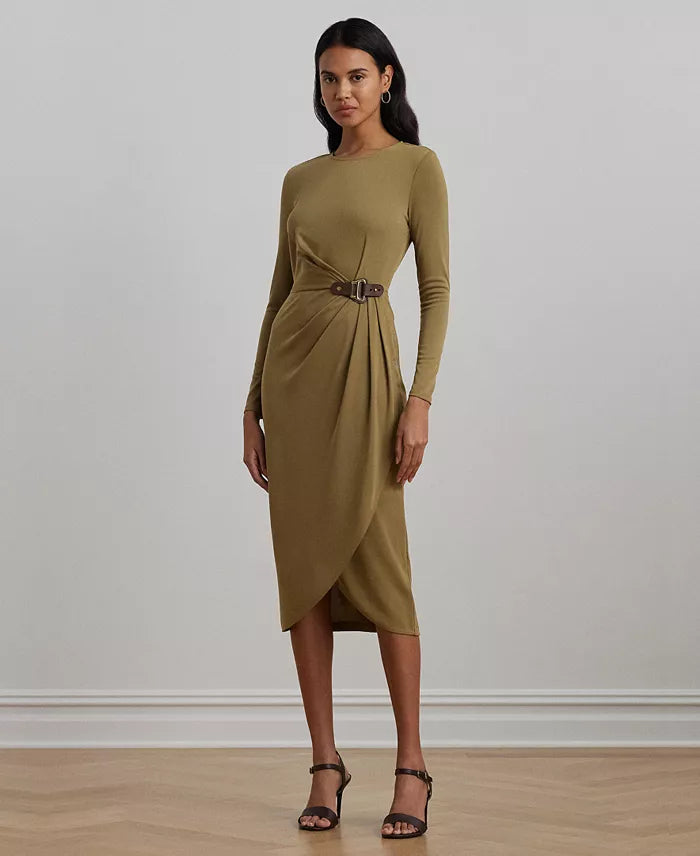 Woman wearing a green dress with a belt against a plain background