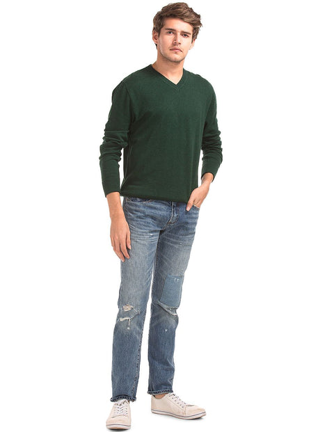 Man wearing a green sweater and blue jeans on a white background