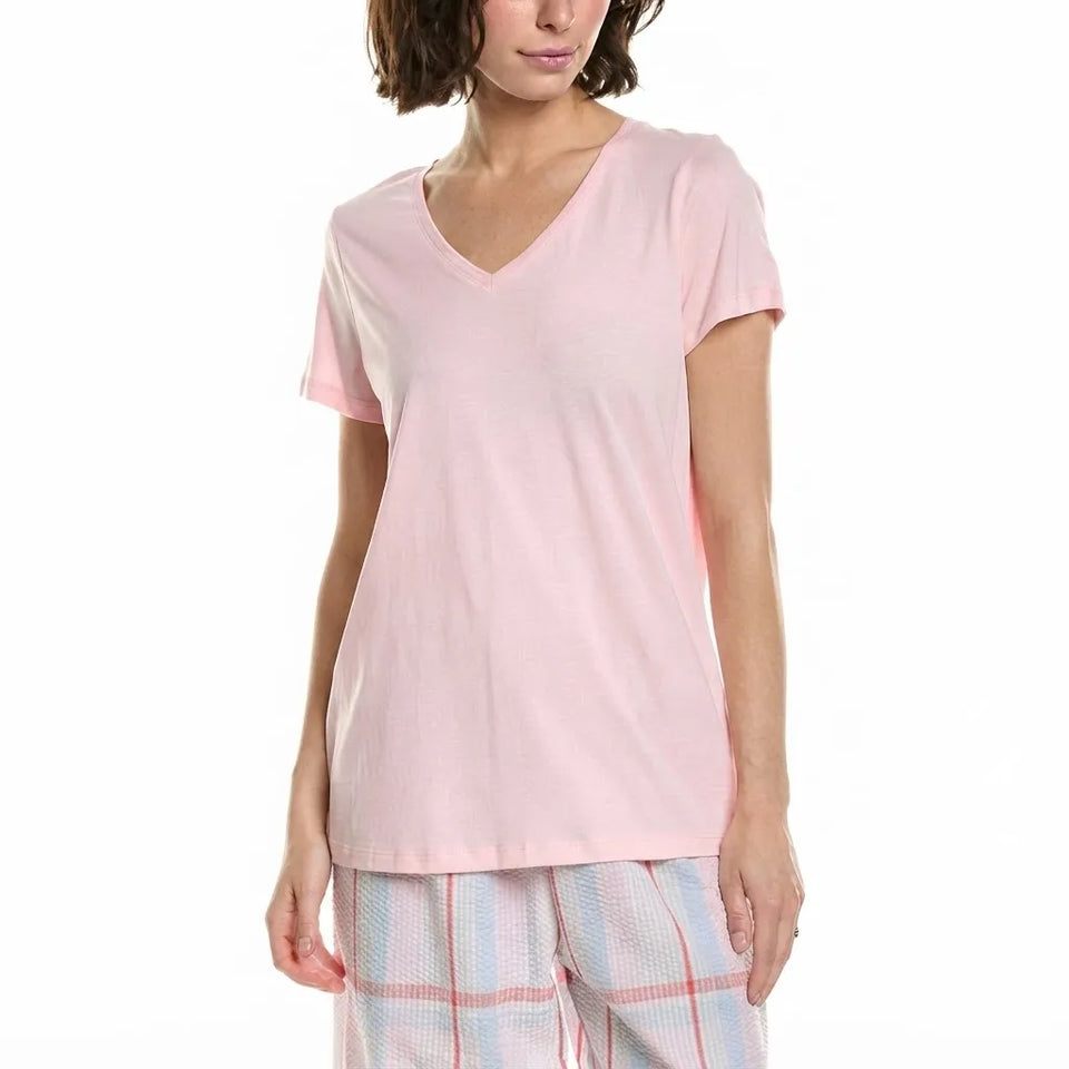 A woman wearing a light pink short-sleeve V-neck t-shirt and pastel plaid pajama pants, shown from the head down against a plain white background.
